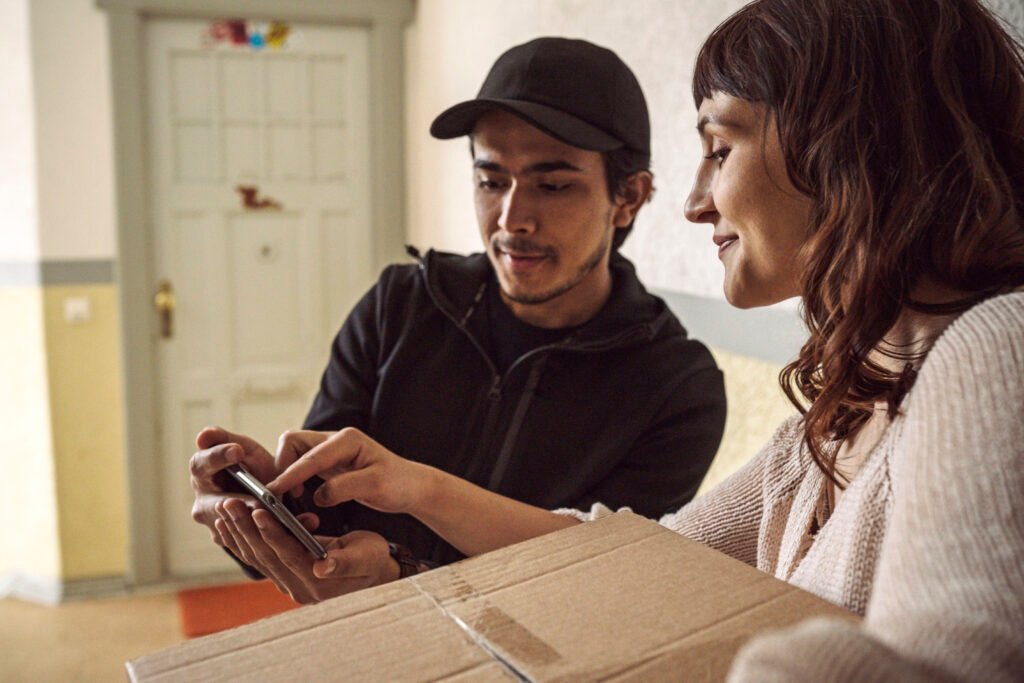 Smiling customer signing on smart phone during package delivery